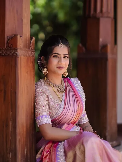 A bride in a beautiful pink and lavender Kanchipuram saree. Her custom blouse is fully embroidered with delicate silver thread, creating a shimmering and ethereal effect.