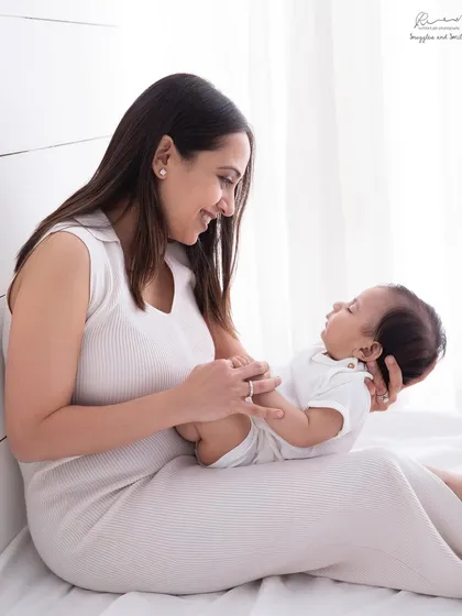My studio is filled with beautiful natural light, perfect for capturing soft, intimate moments like this. A mother's gentle gaze at her newborn tells a story of profound love and connection.