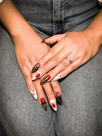 This dramatic stiletto nail set combines red, white, and black with 3D and textured elements, showcasing the high level of creativity in our nail courses.