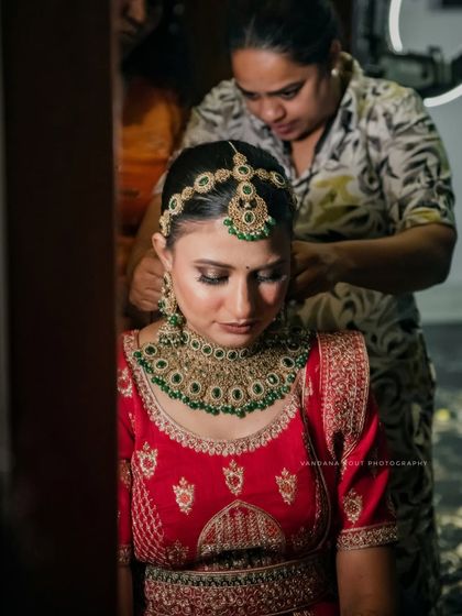 A close-up of the bride getting her hair and matha patti set. These detail shots of the bridal preparation add depth to the wedding album.
