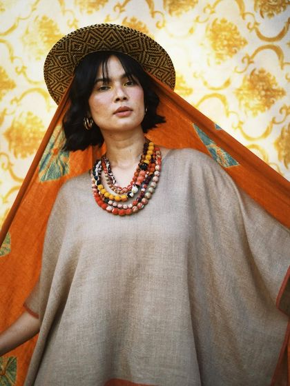 A portrait that feels like a beautiful painting. The combination of the patterned backdrop, the earthy tones of the outfit, and the statement necklace is pure art.