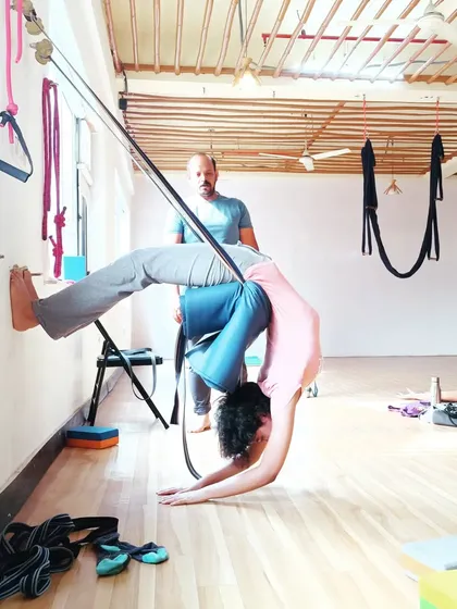 A student works on a deep backbend using the wall ropes. This Iyengar-style method allows for longer holds and a deeper release in the spine.