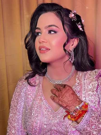 A candid moment showing the bride's henna-adorned hand. The soft waves in her hair and the delicate floral accessories add to the romantic and dreamy vibe of the look.