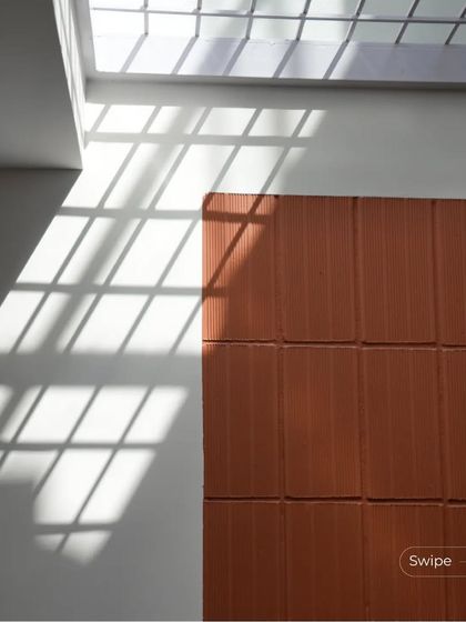 Sunlight streams through a skylight, casting graphic shadows on the floor and a terracotta wall, illustrating the careful consideration of light in my designs.