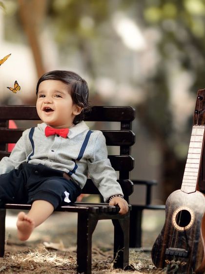 Surrounded by butterflies, this little boy enjoys a moment of pure happiness during his outdoor first birthday photoshoot.