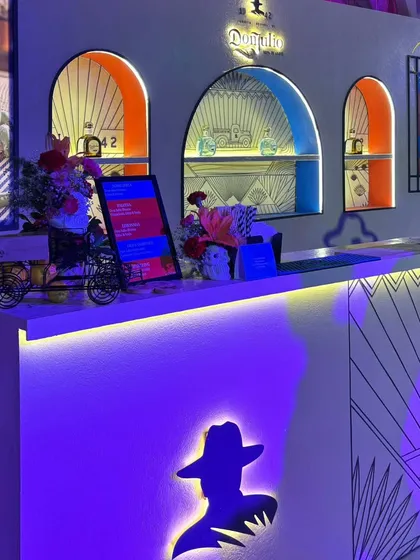 A detailed shot of the Don Julio bar, showing the thoughtful branding details like the illuminated logo silhouette, custom menus on digital screens, and themed decorative elements.
