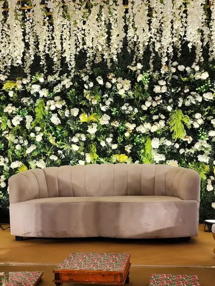 The centerpiece of the Green Vidhi stage, featuring a comfortable sofa for the couple, framed by a wall of white flowers and hanging wisteria.