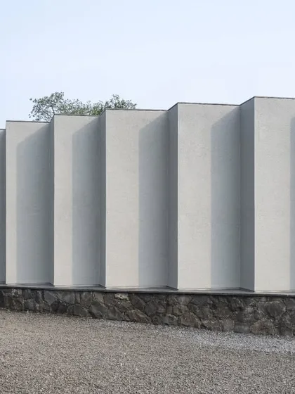 The exterior wall of the Vismaya museum is articulated with a series of deep, vertical fins. This creates a rhythmic facade that changes in appearance with the movement of the sun, playing with light and shadow throughout the day.