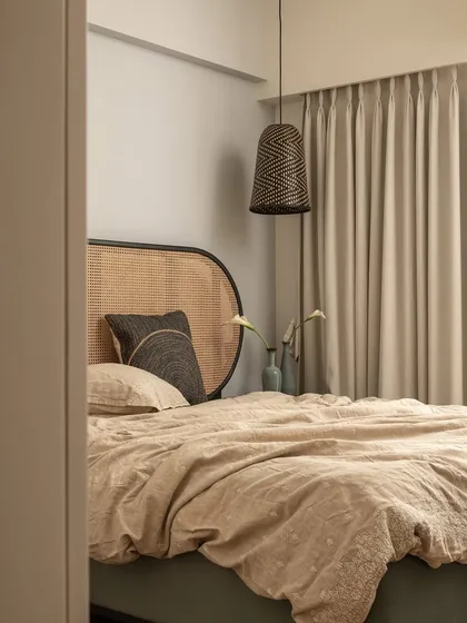This view of the guest bedroom captures its serene and minimalist aesthetic. The pendant light with its intricate pattern casts a warm glow, complementing the natural textures in the room.