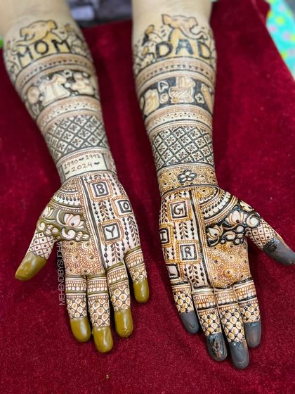 A clear, top-down view of the personalized "Mom" and "Dad" baby shower mehendi, showing the different patterns on each hand.