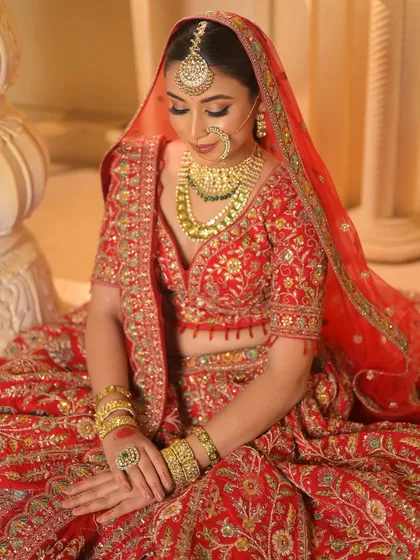 A full-body shot of the bride seated, her red lehenga spread out in all its glory. This is the epitome of bridal grandeur.