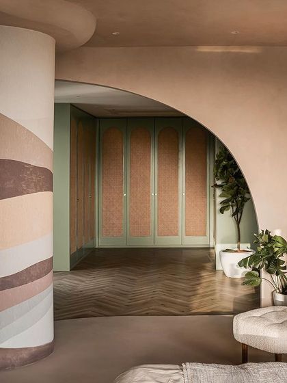 A view from the bedroom into the walk-in closet, where sage green and cane doors add a touch of color and texture to the earthy palette.