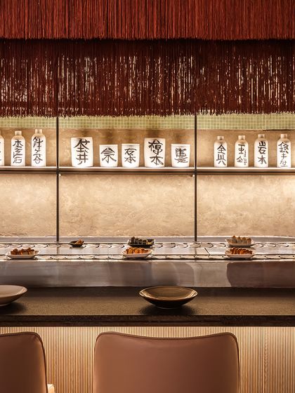 A closer look at the sushi conveyor belt and the warm, ambient light that enhances the details of the space. The back-lit shelf with Japanese pottery adds a touch of authentic, traditional character.