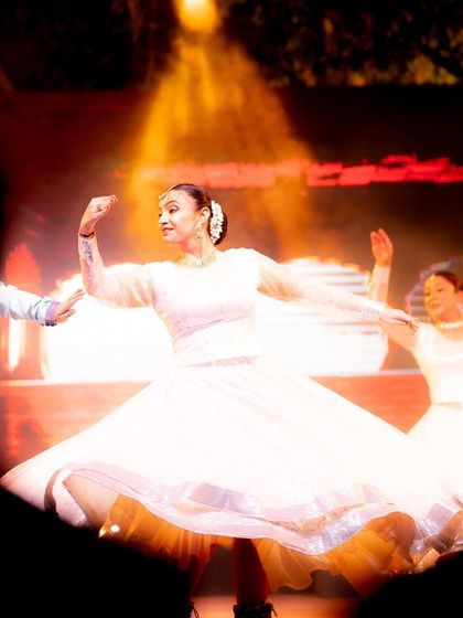 A dancer in a white dress twirls, her skirt catching the warm stage light beautifully. This is a great example of capturing motion and the flow of fabric to add energy to a still photograph.