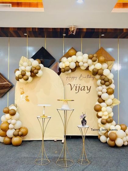 A full view of the earthy-toned birthday setup for Vijay. The double-arched backdrops and organic balloon arrangement create a calm, modern, and stylish atmosphere.