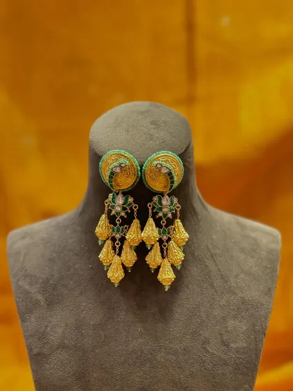 Jewelry that turns heads. These green and gold jhumkas feature a beautiful stud with delicate tassels, adding graceful movement with every turn.