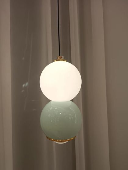 A minimalist pendant light featuring a stacked design with a glowing upper sphere and a solid-colored base. It's a simple yet chic addition to any modern room.