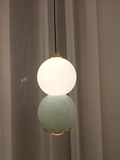 A minimalist pendant light featuring a stacked design with a glowing upper sphere and a solid-colored base. It's a simple yet chic addition to any modern room.