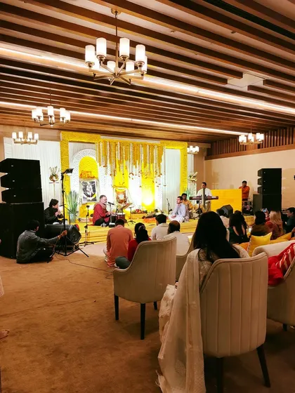 Guests seated for a soulful Sai Sandhya. The decor is kept serene and spiritual, with a focus on the stage which is decorated with yellow floral garlands.