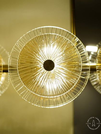 A linear chandelier featuring an arrangement of clear and amber-tinted textured glass discs. This fixture provides both direct and ambient light, adding a layer of sophistication and warmth to dining areas and boardrooms.