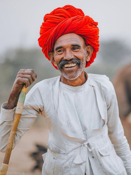 A heartwarming smile from a man in a vibrant red turban in Rajasthan. This portrait captures the cheerful and welcoming spirit of the Rajasthani people.