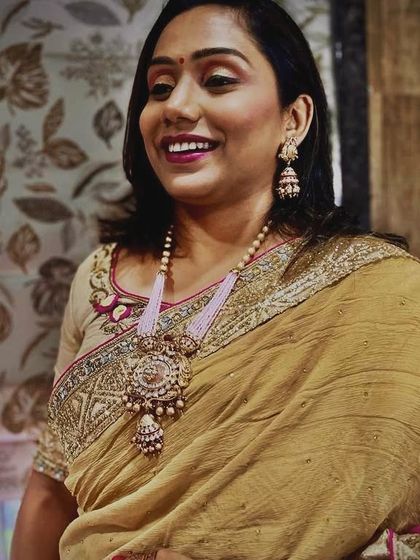 Another shot of the client, smiling brightly. The long necklace elongates the torso and works beautifully with her gold-toned saree.