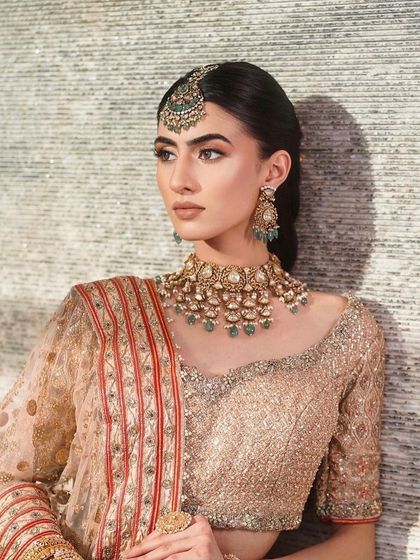 This look showcases a soft, peachy-gold bridal lehenga. The makeup is warm and glowing, with a focus on a radiant complexion and subtly smoked-out eyes for an elegant and understated feel.