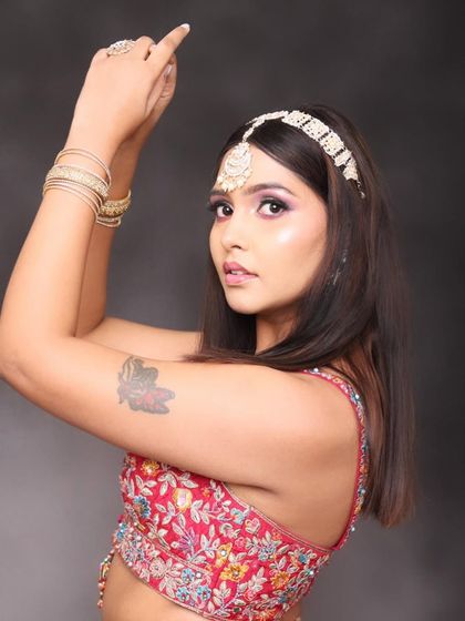 This angle shows off the beautiful details of the makeup. The subtle purple tones in the eyeshadow pick up the colors in the embroidered blouse, creating a cohesive and well-planned look.