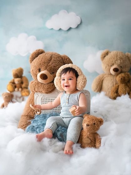 Keeping his ears warm with fluffy earmuffs, this baby boy is all smiles in his cloudy, teddy bear world.