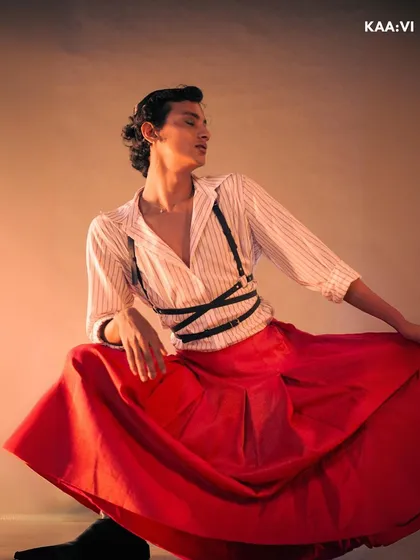 This seated pose showcases the beautiful drape and volume of the skirt, a key element of this androgynous, high-fashion concept.