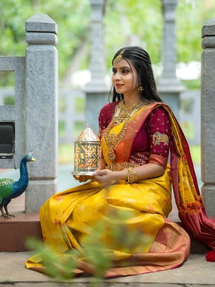 Holding a traditional lantern, the model looks like a princess from a fairytale in her yellow and red silk saree.