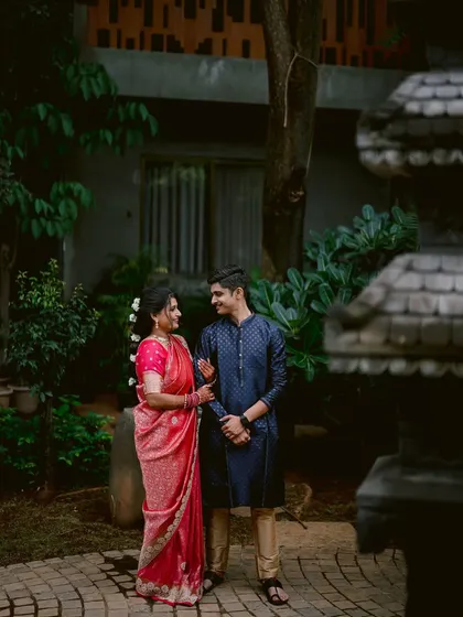 Apeksha and Rutwij share a look of love in a quiet garden setting. The vibrant pink of her saree contrasts beautifully with his deep blue kurta, making for a striking couple portrait.