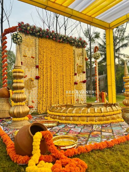 A beautiful shot of our outdoor Haldi setup, ready for the ceremony. The combination of the marigold backdrop, the lotus 'urli', and the traditional props creates a scene of pure bliss.