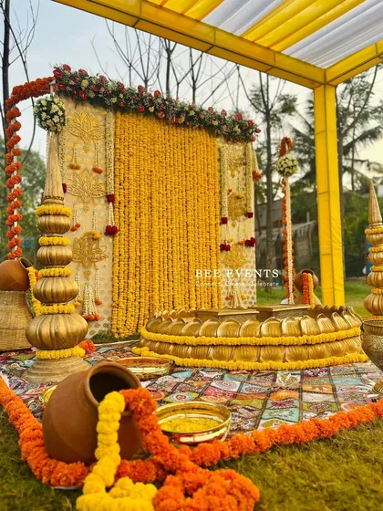 A beautiful shot of our outdoor Haldi setup, ready for the ceremony. The combination of the marigold backdrop, the lotus 'urli', and the traditional props creates a scene of pure bliss.