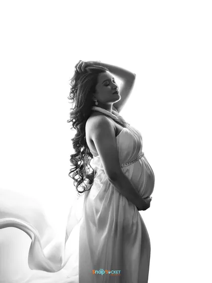 I have a real soft spot for classic black and white portraits. This high-contrast studio shot focuses on the beautiful silhouette of the mom-to-be. The flowing drape adds a touch of artistic flair, creating a timeless and elegant image.