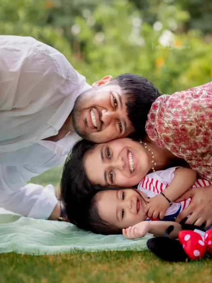 A happy pile of love! This family shares a laugh while relaxing on a blanket in the park, creating a warm and authentic family portrait.