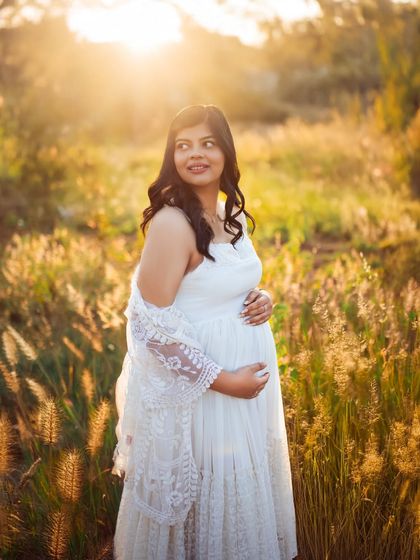 A close up shot capturing the mother's happy glow. The golden light of the sunset illuminates her, highlighting the joy and anticipation of this special time.