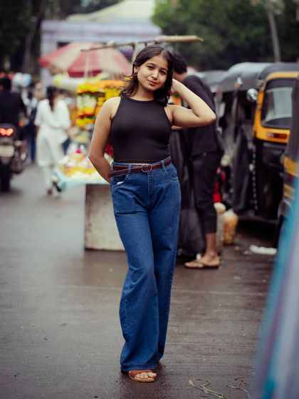 A full-length portrait on a rainy Mumbai street. The wet ground and overcast sky create a unique, moody atmosphere for this urban shot.