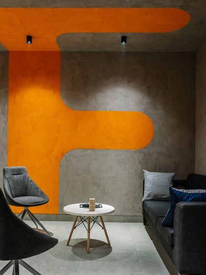 In the basement lounge, we used bold orange graphics on the concrete-finish walls to create a vibrant and energetic atmosphere for informal meetings and relaxation.