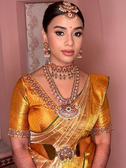 A stunning Muhurtham look featuring bold, defined eyes and a perfectly matched lip color that enhances the warmth of her golden-yellow saree.