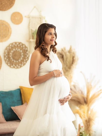 A three-quarters portrait capturing the soft textures of the white gown and the gentle expression of the mom-to-be.