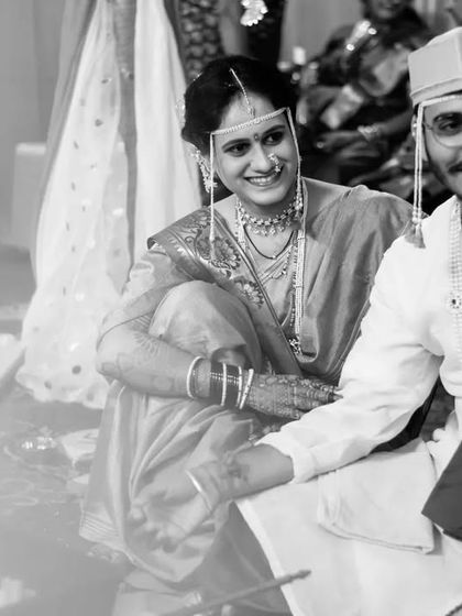 A candid black and white shot of the bride and groom sharing a smile during their wedding ceremony, capturing a moment of shared happiness.