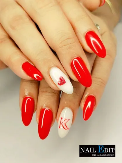 A classic Valentine's set with bold red almond-shaped nails. The accent nails feature a delicate heart and a custom initial, making it a personalized and romantic choice.