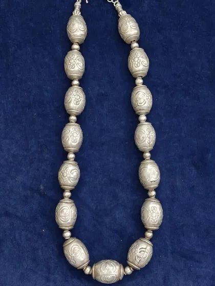 A unique and antique silver statement chain. This necklace is made of large, hollow silver beads, each intricately carved with floral patterns.