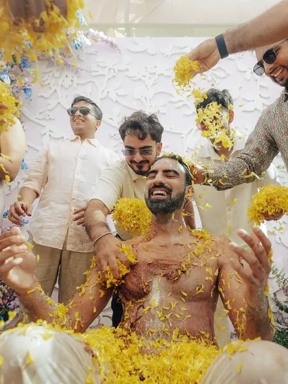 The groom's friends showering him with flowers and laughter. The haldi is a time for the whole squad to come together and celebrate.