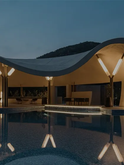 The reflection of the Aqua Pool & Spa's illuminated structure on the water at night, showcasing the project's striking form.