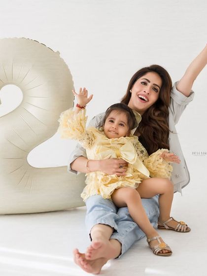 Pure joy and celebration! A mother and daughter wave happily during a fun and energetic second birthday photo session.