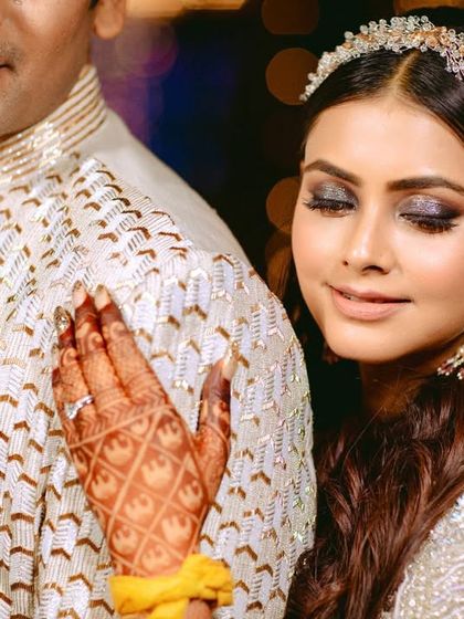 A close-up shot focusing on the bride's intricate henna and her gentle touch on the groom's shoulder.