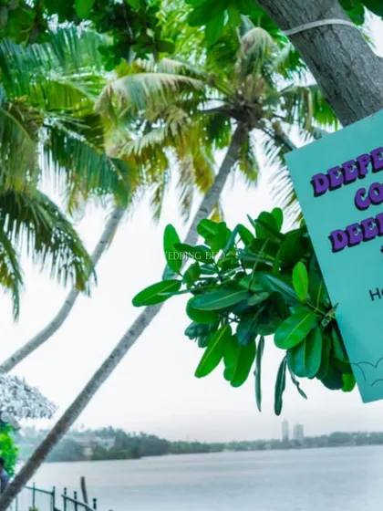 A playful sign for the "Henna Lounge" hangs from a tree overlooking the water, inviting guests to get their Mehendi done with a beautiful view.