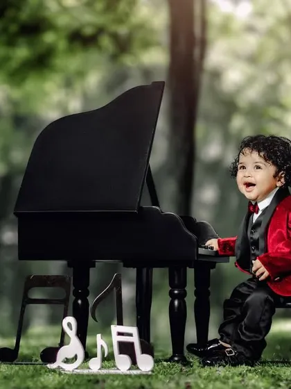 The world through the eyes of a child is pure magic. A boy in a red velvet jacket laughs with joy at his piano.